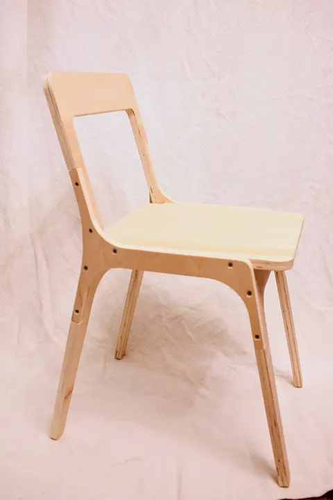 A plywood chair seen from the side against a white wall