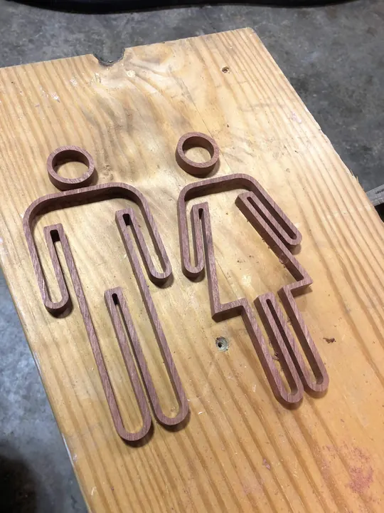 Restroom sign figures cut into a plywood board