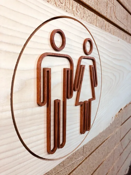 A round restroom sign with dark inlaid figures