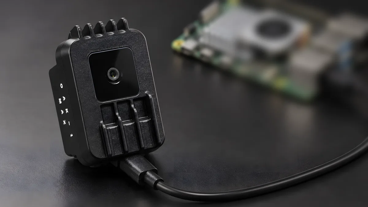 A Luxonis OAK-1 Max camera, its USB-C cable running to a Raspberry Pi 5 behind it